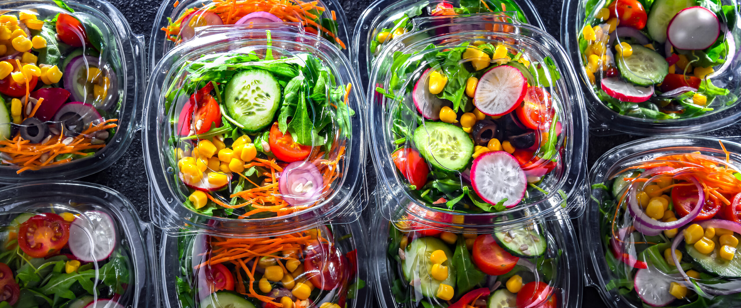 Boxes with pre-packaged vegetable salads in a commercial fridge